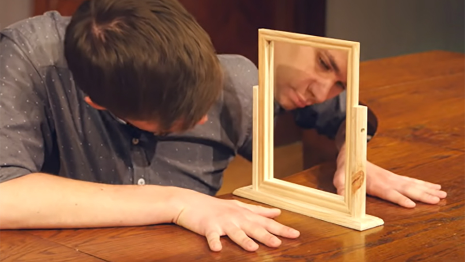 Person holding hands on either side of a mirror