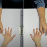 Two hands are spread on a table, a person opposite is holding the little finger tips on each hand